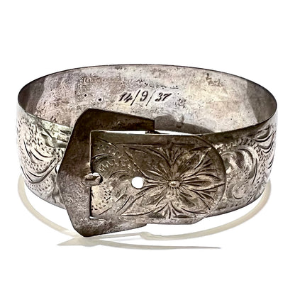 Vintage sterling silver Art Nouveau style women's bracelet featuring a buckle motif with a floral design etched into the metal.  On the inside of the piece, the date "14/9/37" are visibly engraved in old script font Arabic numbers.