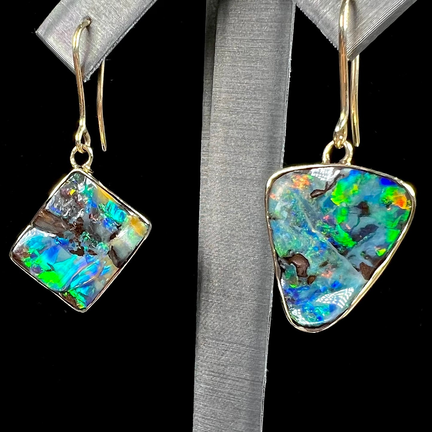 An asymmetric pair of French wire dangle yellow gold boulder opal earrings.  One opal is a square, and the other is a triangle.