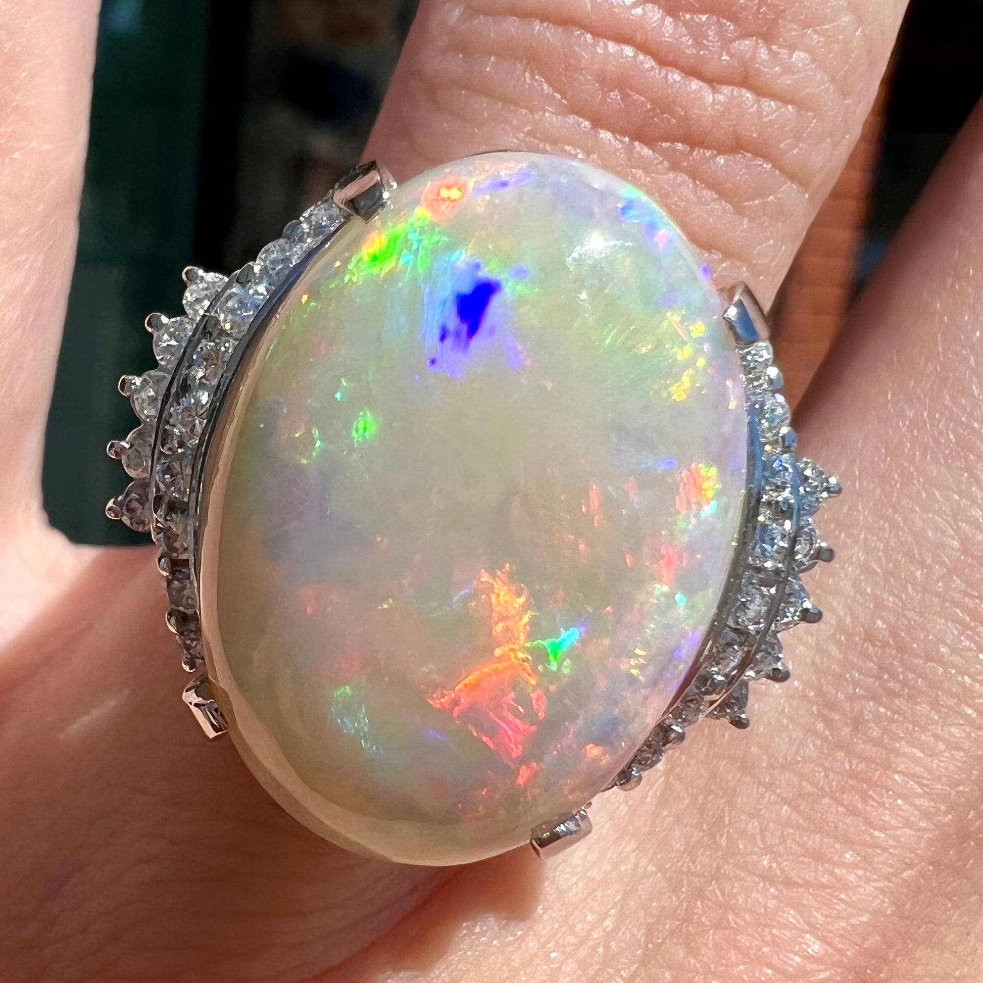 An oval cabochon cut Coober Pedy, Australian opal prong set in a platinum ring with round cut diamonds.