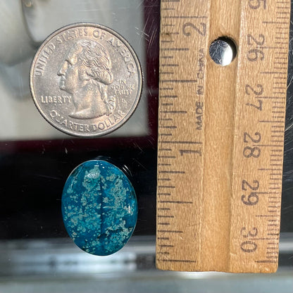 A loose, oval cabochon cut turquoise stone from Morenci, Arizona.  The stone has azurite inclusions.
