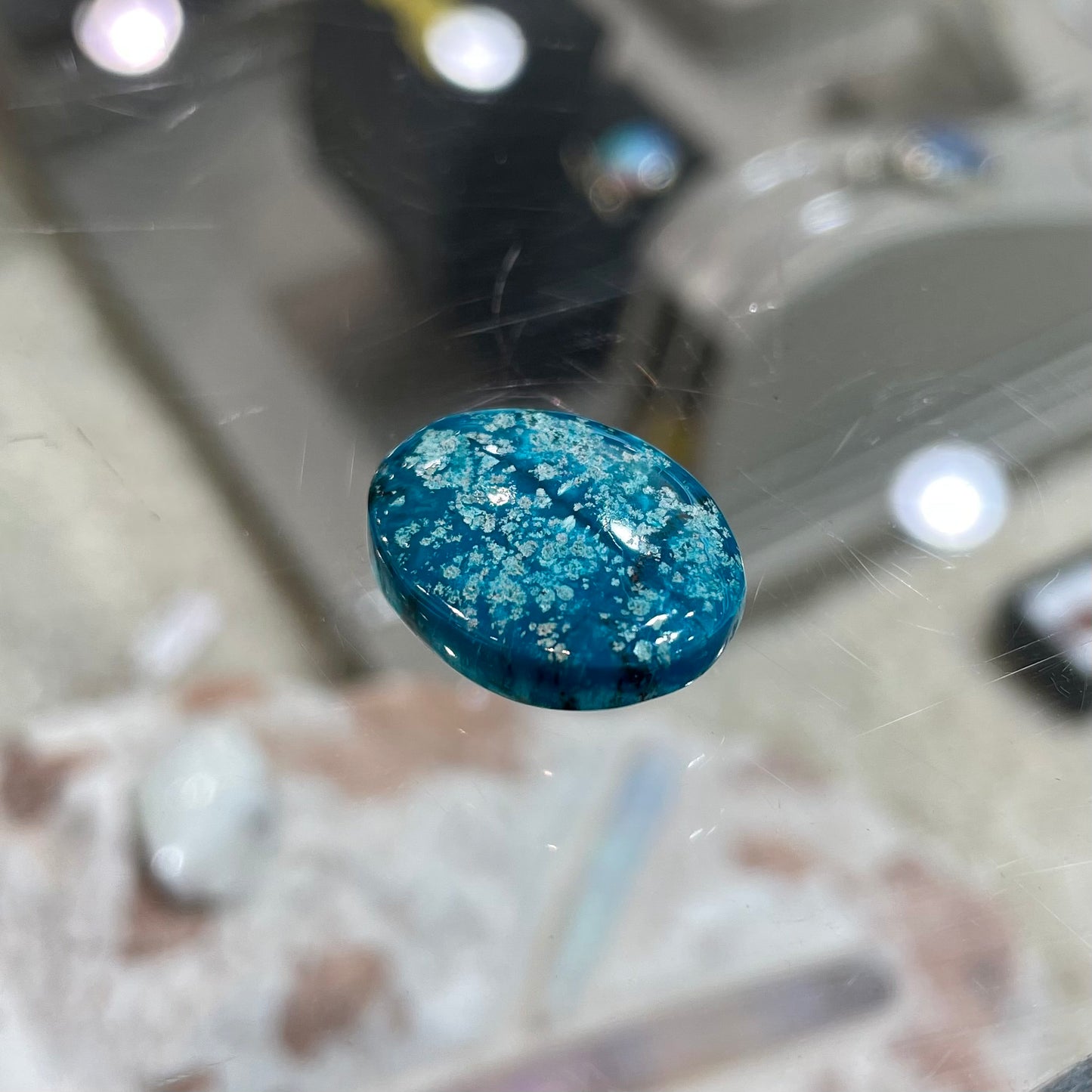 A loose, oval cabochon cut turquoise stone from Morenci, Arizona.  The stone has azurite inclusions.