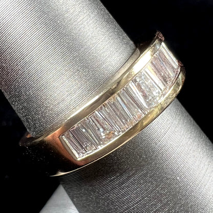 A ladies' yellow gold ring channel set with a row of baguette cut diamonds.