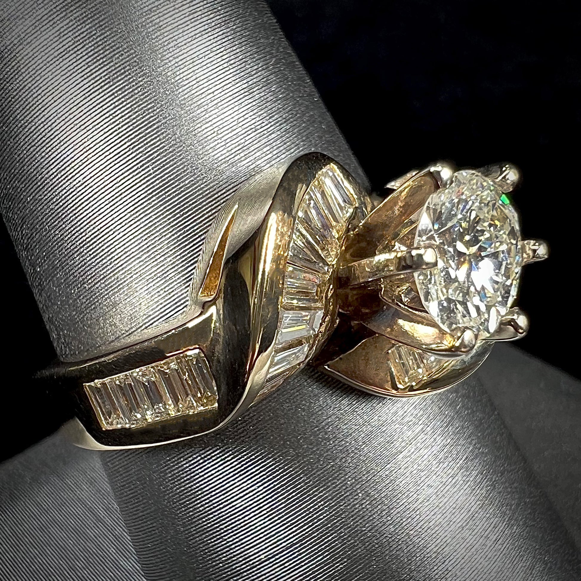 A ladies' yellow gold engagement ring set with a 0.77ct oval cut diamond and baguette cut diamond accents.