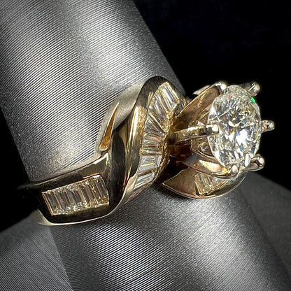 A ladies' yellow gold engagement ring set with a 0.77ct oval cut diamond and baguette cut diamond accents.