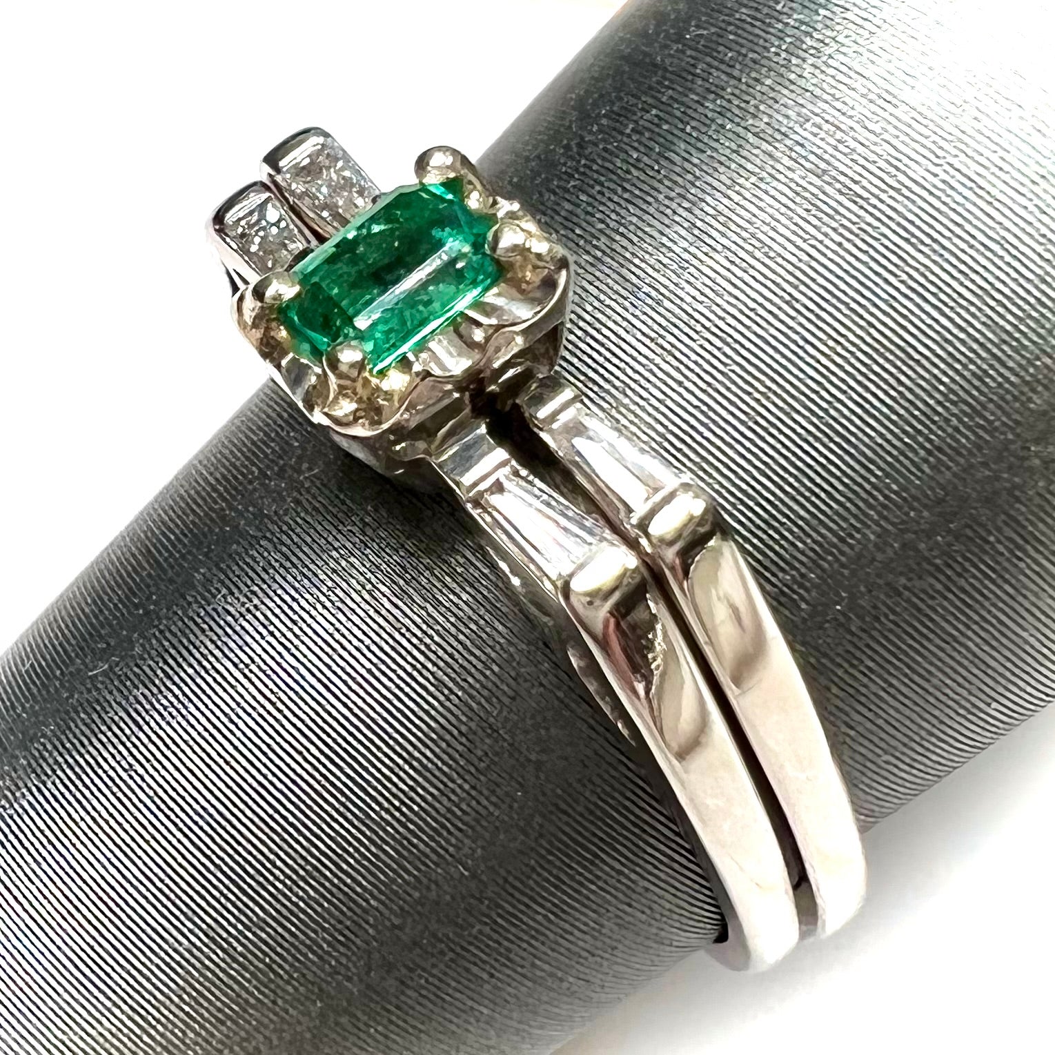 A white gold emerald and baguette cut diamond engagement and wedding set.