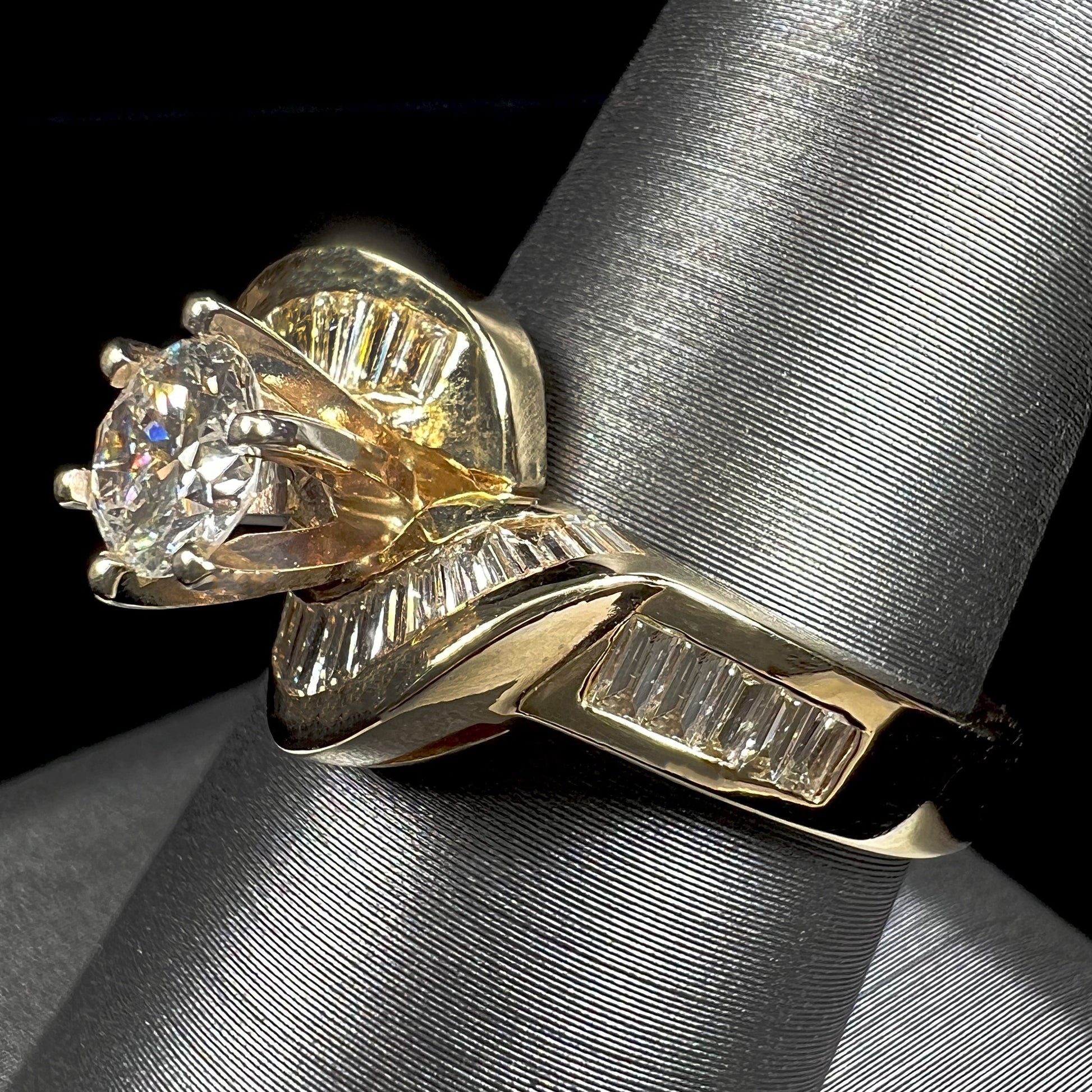 A ladies' yellow gold engagement ring set with a 0.77ct oval cut diamond and baguette cut diamond accents.