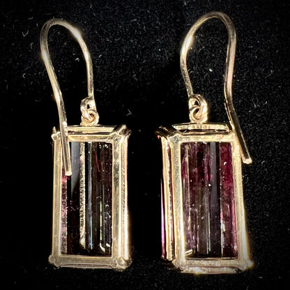 A pair of pink and magenta bicolor tourmaline dangle earrings handmade in 14kt yellow gold with basket settings and shepherd's hooks.