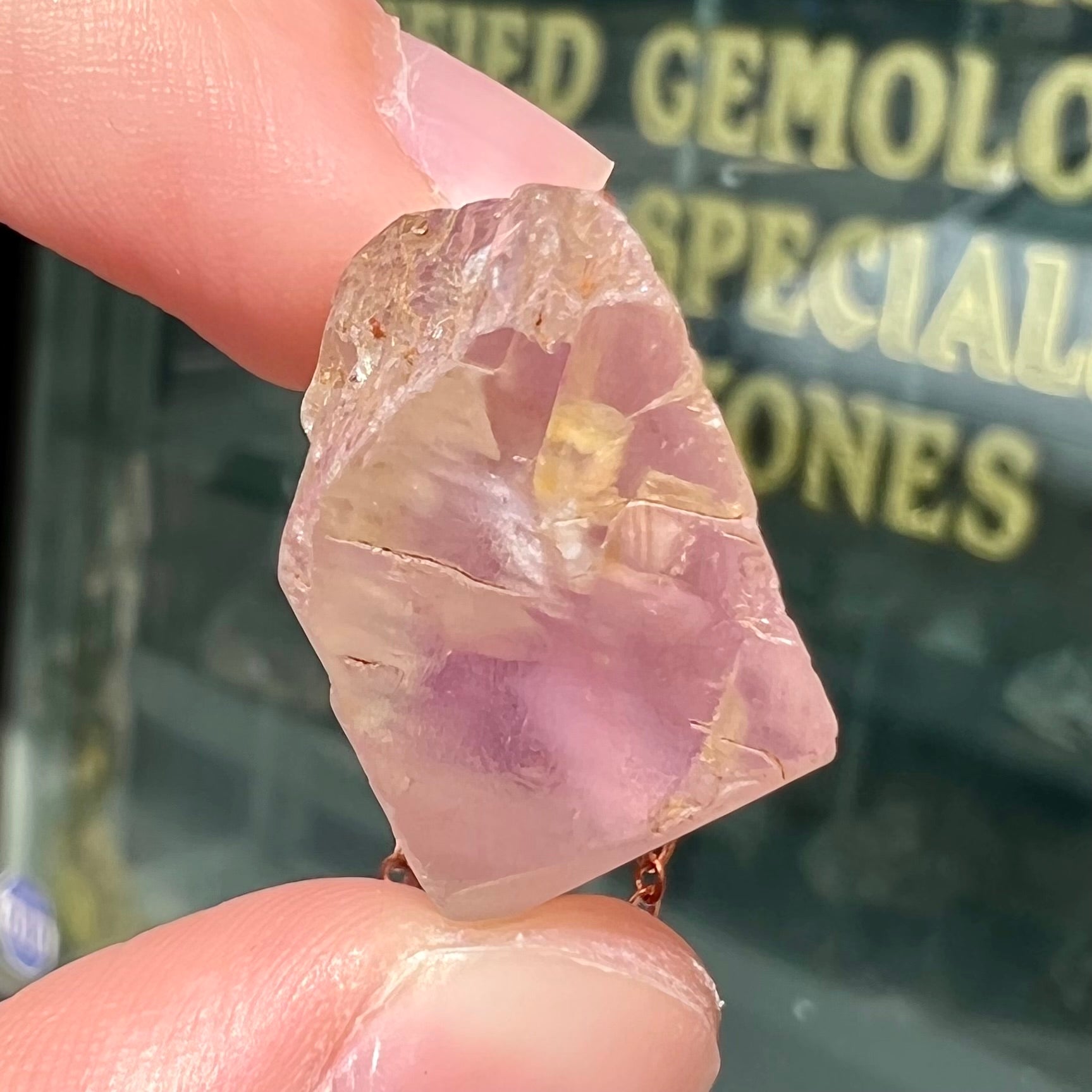A drilled bicolor spodumene crystal hanging on a copper cable chain.  The crystal is pink and yellow, or kunzite and triphane respectively.
