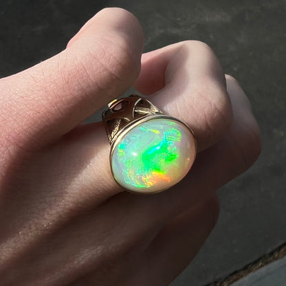 A custom yellow gold men's ring set with two diamonds and a large oval cabochon cut opal from Magdalena, Mexico.