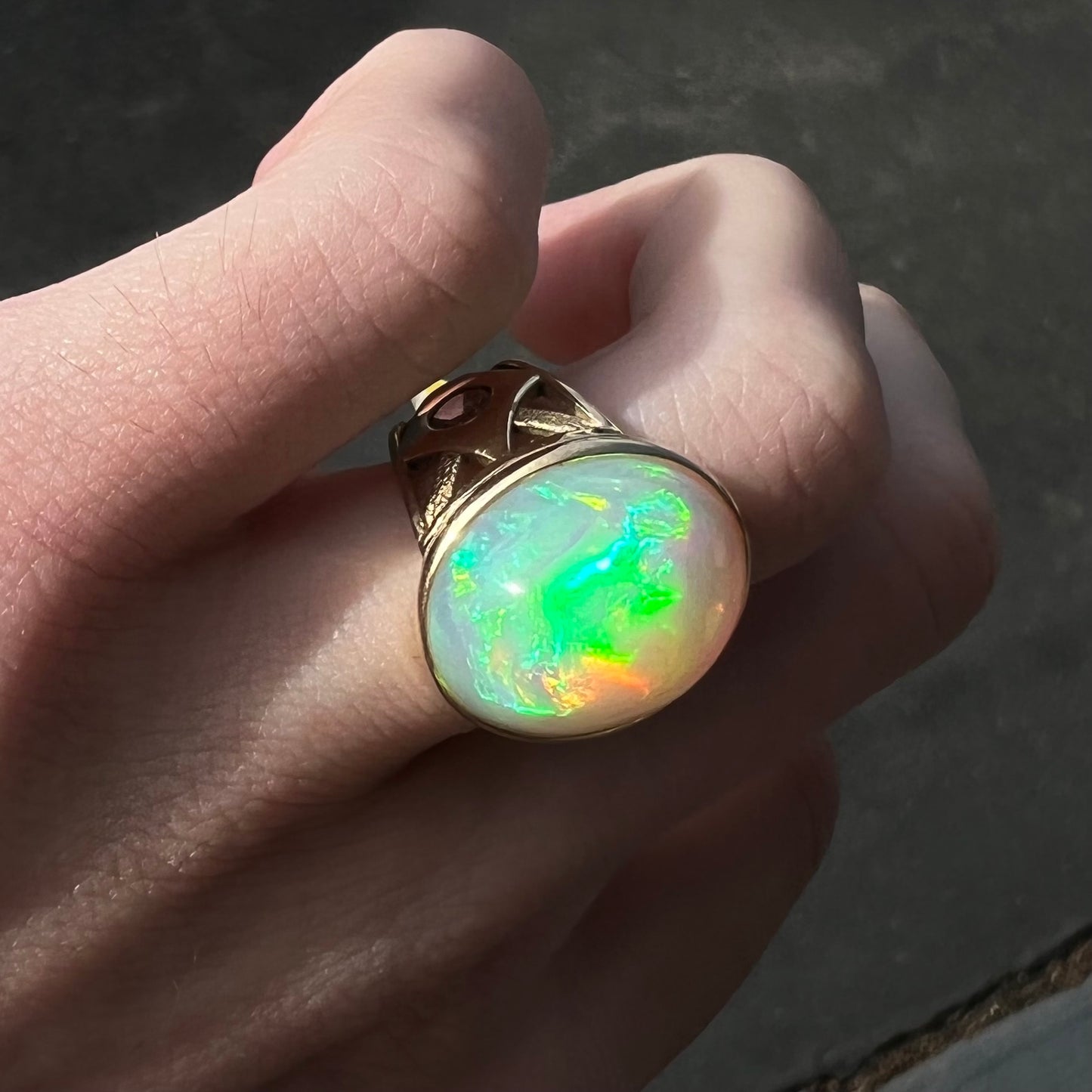 A custom yellow gold men's ring set with two diamonds and a large oval cabochon cut opal from Ethiopia, Africa.