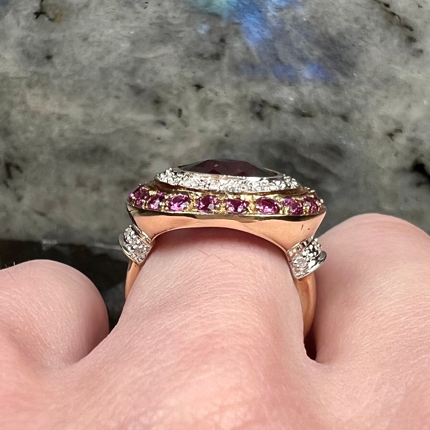 A yellow gold garnet and diamond halo ring set with a checkerboard cut rhodolite garnet center stone.