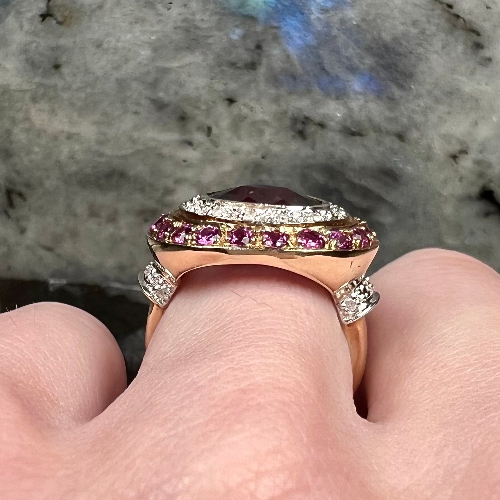 A yellow gold garnet and diamond halo ring set with a checkerboard cut rhodolite garnet center stone.