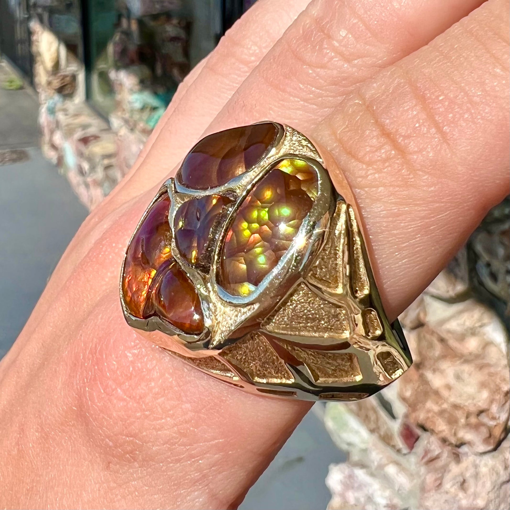 A yellow gold men's thug ring set with four fire agate stones resembling a spooky face.