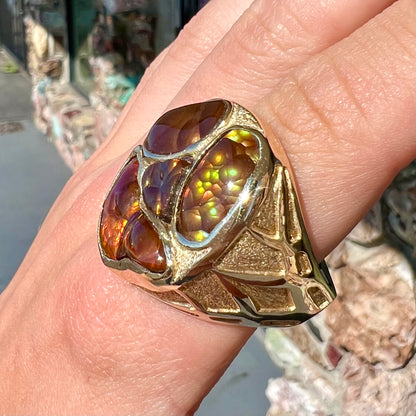 A yellow gold men's thug ring set with four fire agate stones resembling a spooky face.