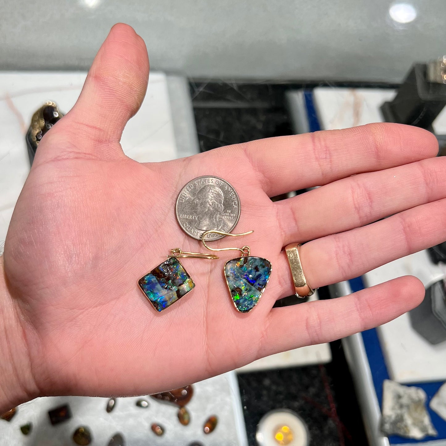 An asymmetric pair of French wire dangle yellow gold boulder opal earrings.  One opal is a square, and the other is a triangle.