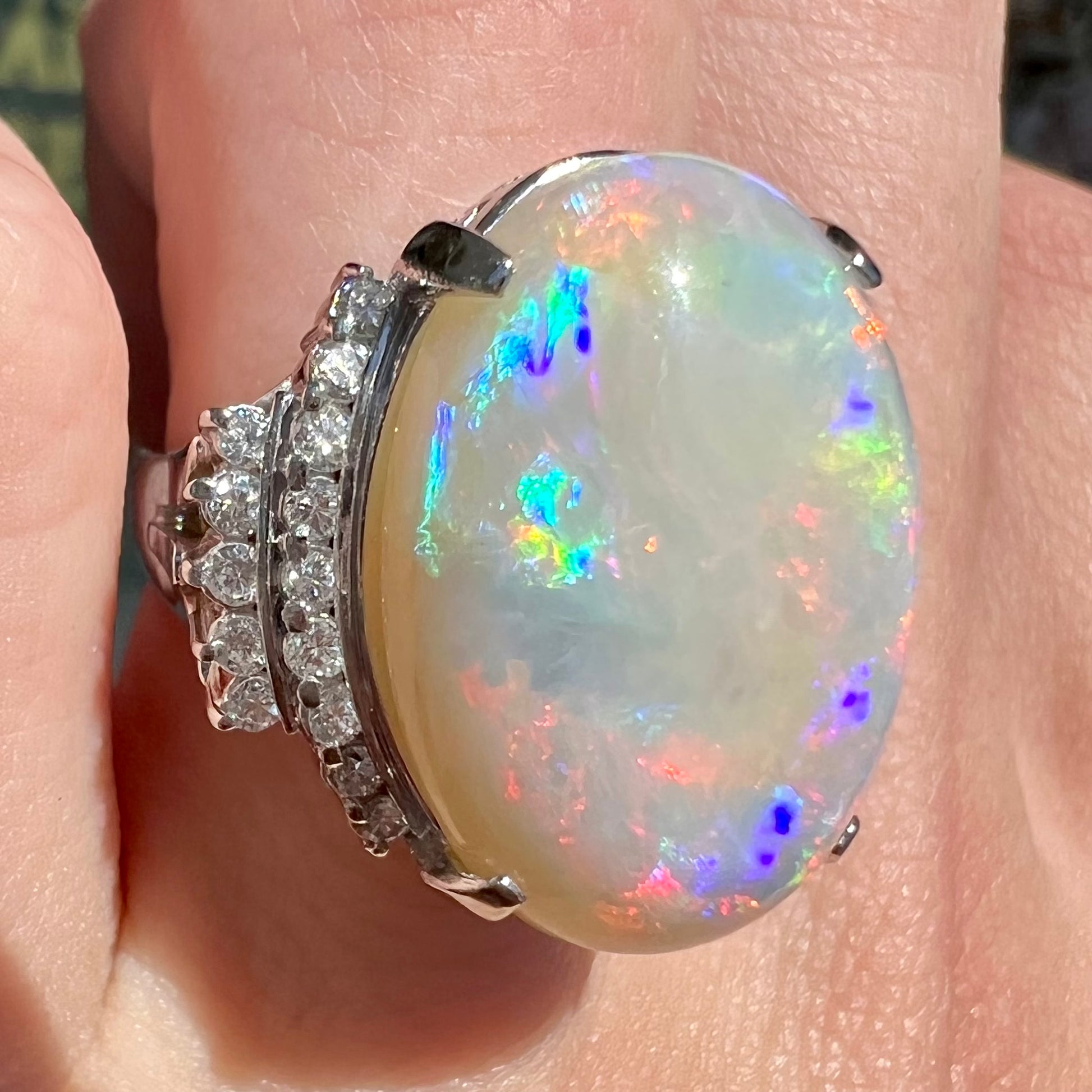An oval cabochon cut Coober Pedy, Australian opal prong set in a platinum ring with round cut diamonds.