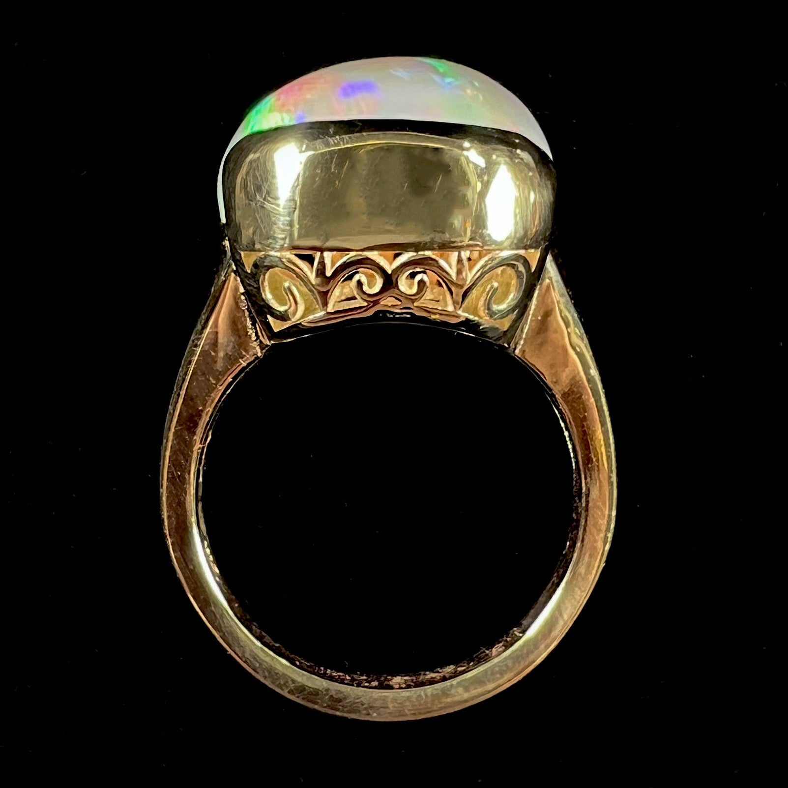 A ladies' yellow gold split shank ring half-bezel set with a barrel cabochon cut natural Ethiopian fire opal stone.