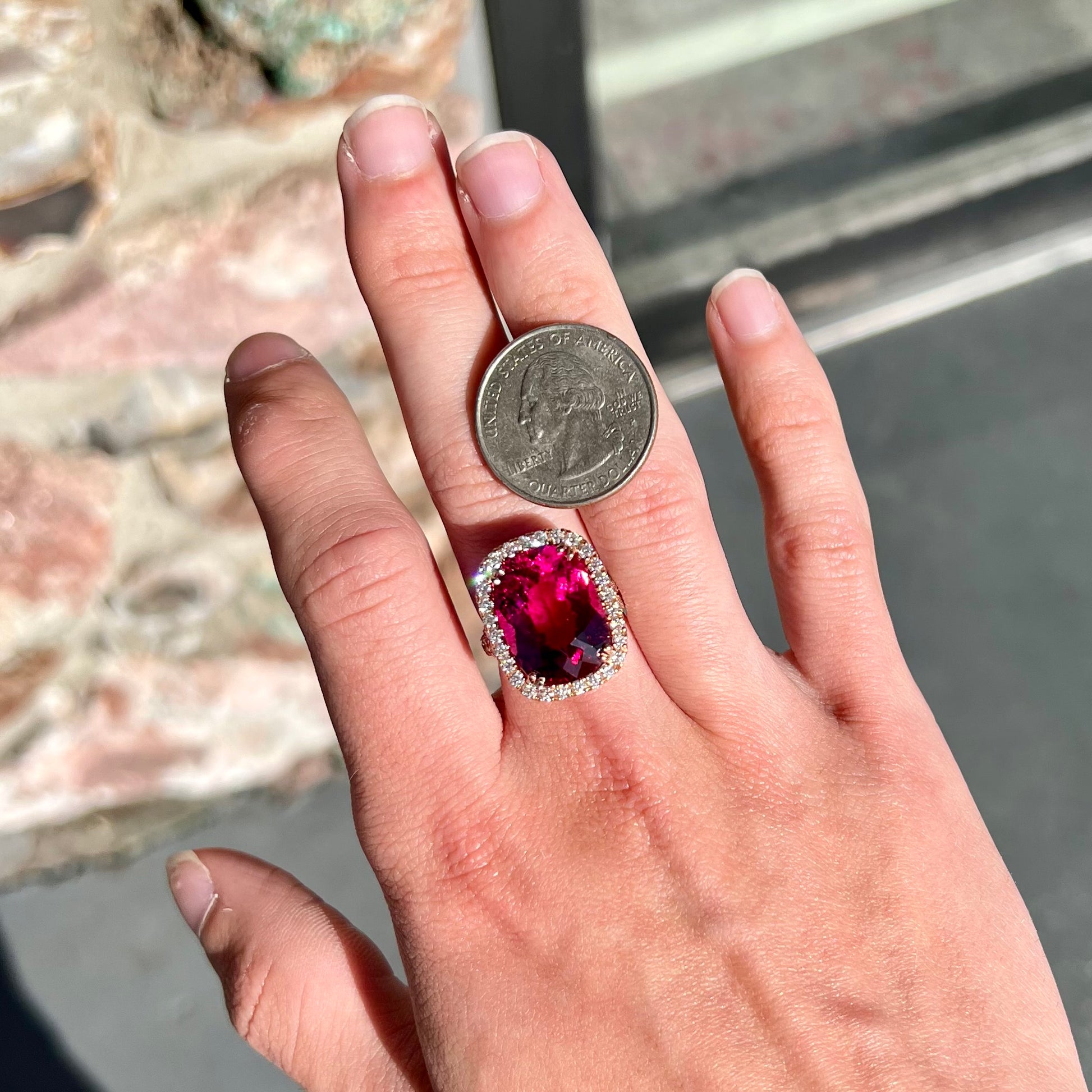 A rose gold, split shank engagement ring set with a cushion cut rubellite tourmaline in a diamond halo.