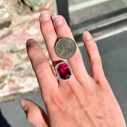 A rose gold, split shank engagement ring set with a cushion cut rubellite tourmaline in a diamond halo.