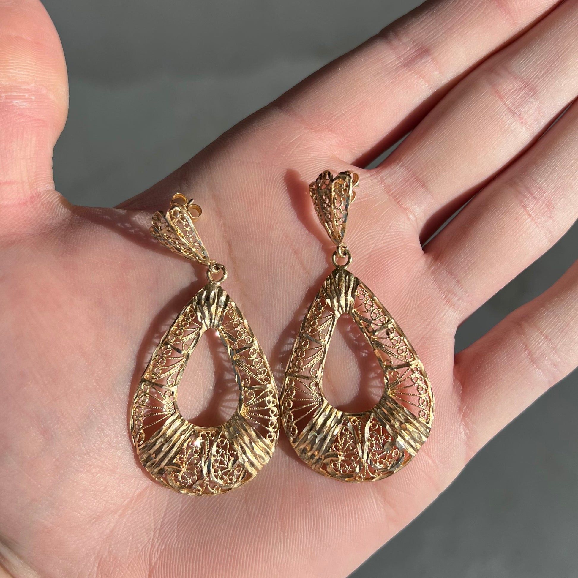A pair of 14kt yellow gold filigree dangle earrings.  The earrings have a pear shape open design.