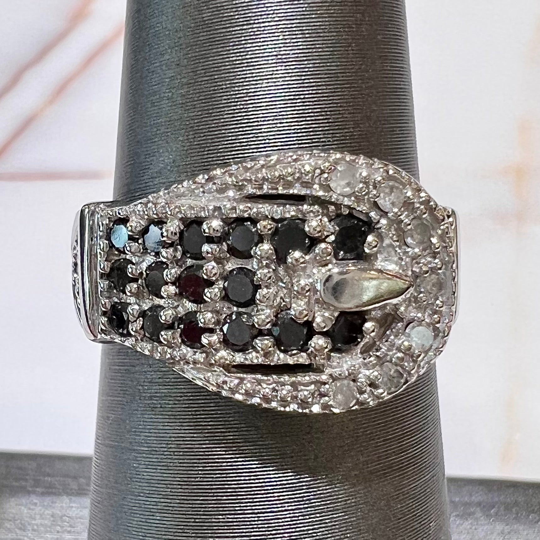 A white gold buckle ring pave set with round black and white diamonds.