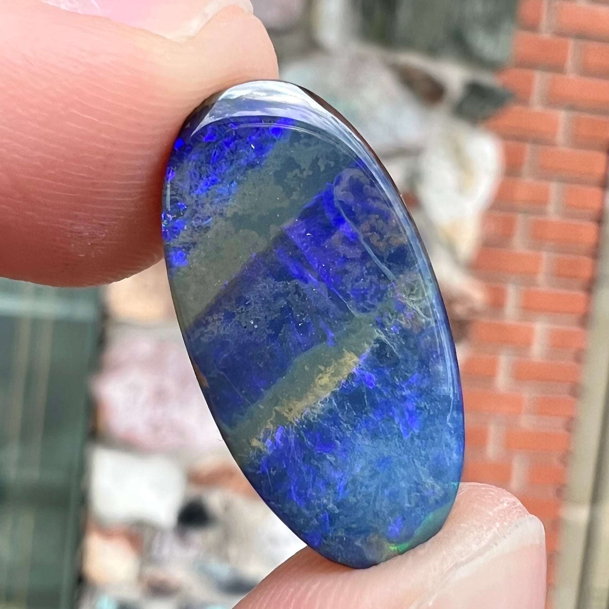 A loose, oval cabochon cut black boulder opal stone from Quilpie, Australia.