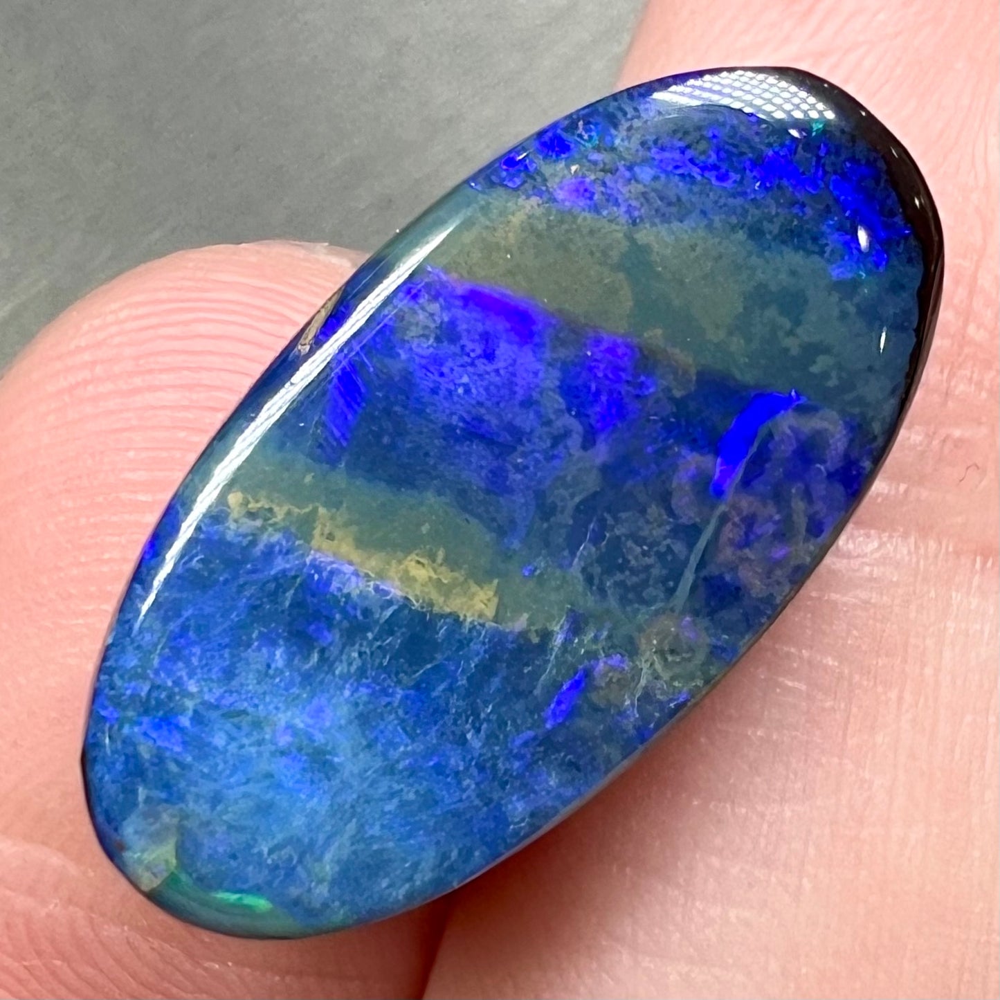 A loose, oval cabochon cut black boulder opal stone from Quilpie, Australia.