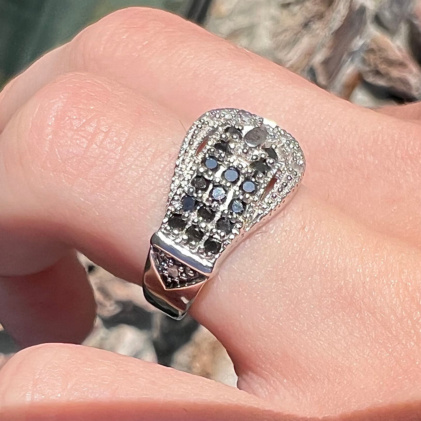 A white gold buckle ring pave set with round black and white diamonds.