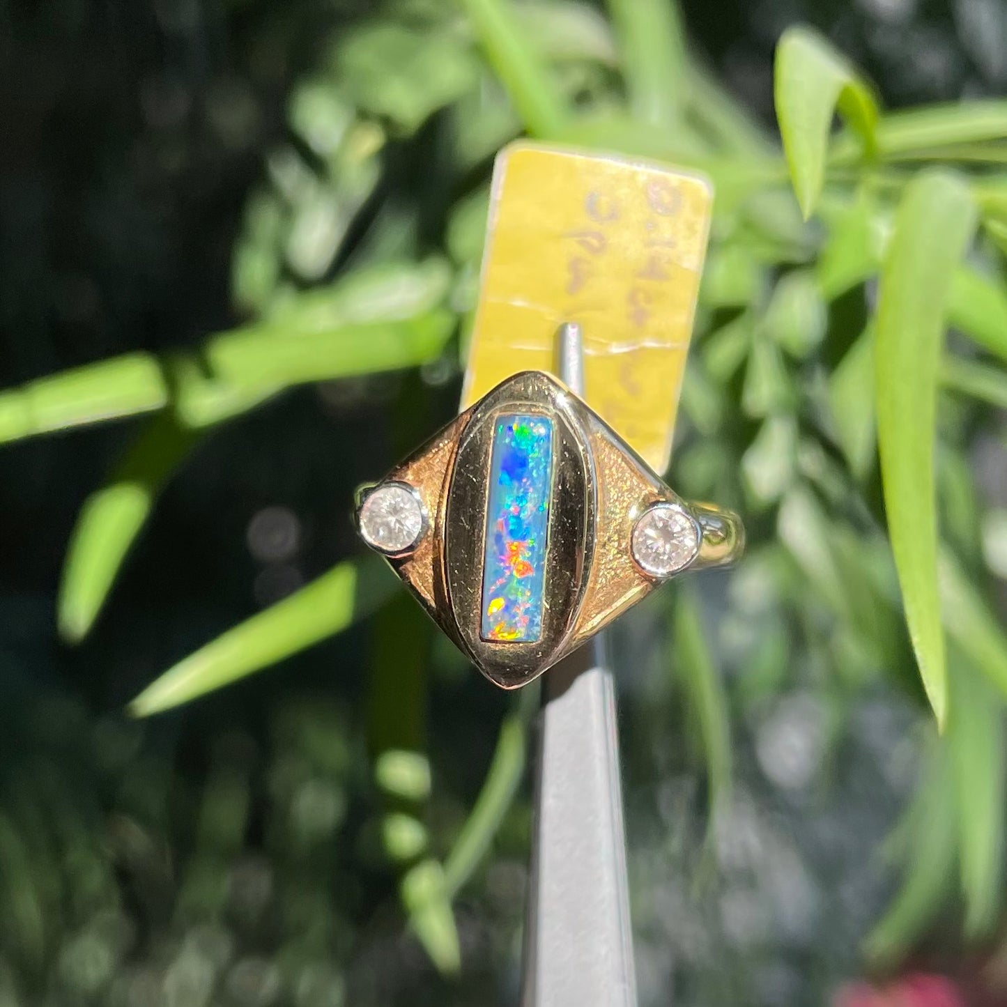 Lightning Ridge black opal set between two round diamonds in an 18 karat yellow gold ring.  Anaheim, California.