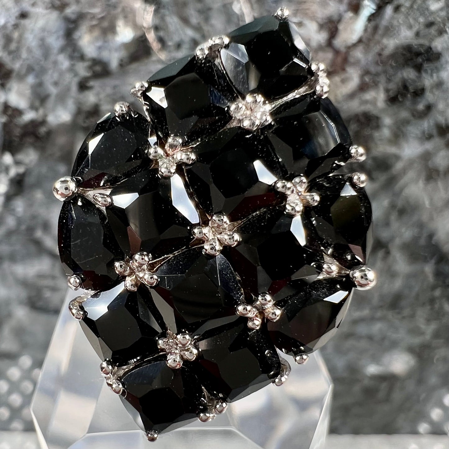 A sterling silver ring cluster set with faceted black spinel stones set to form a marquise shape.