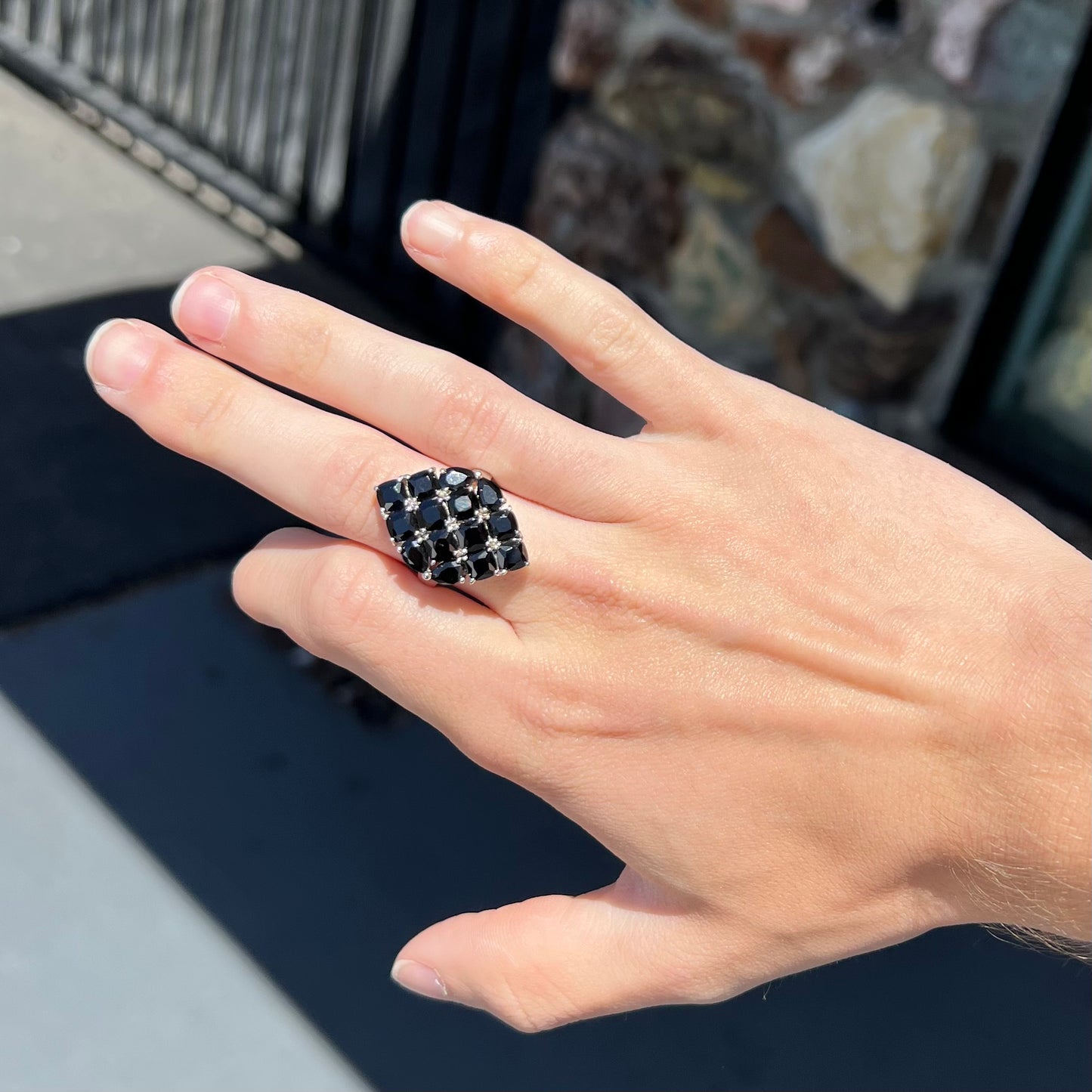 A sterling silver ring cluster set with faceted black spinel stones set to form a marquise shape.