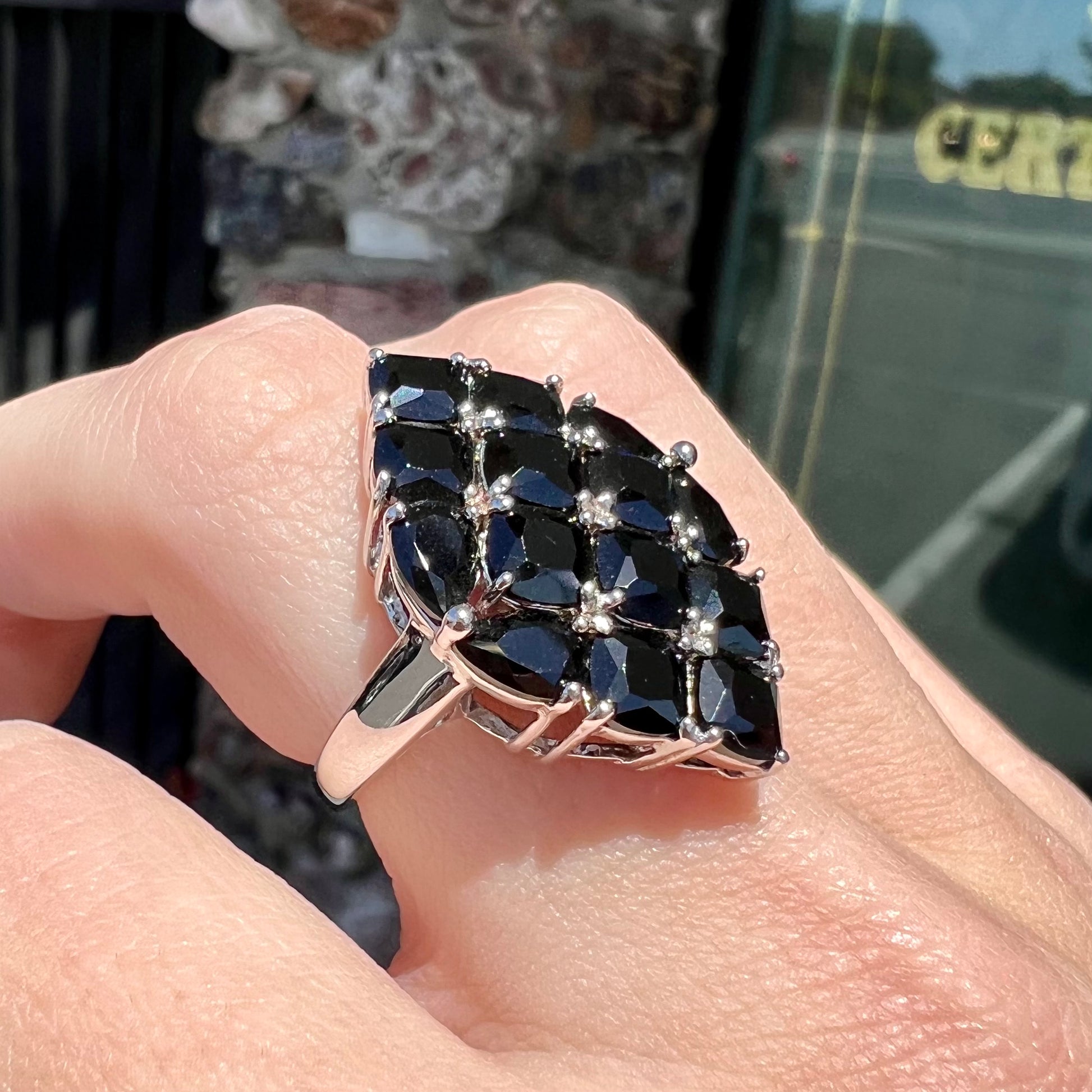 A sterling silver ring cluster set with faceted black spinel stones set to form a marquise shape.