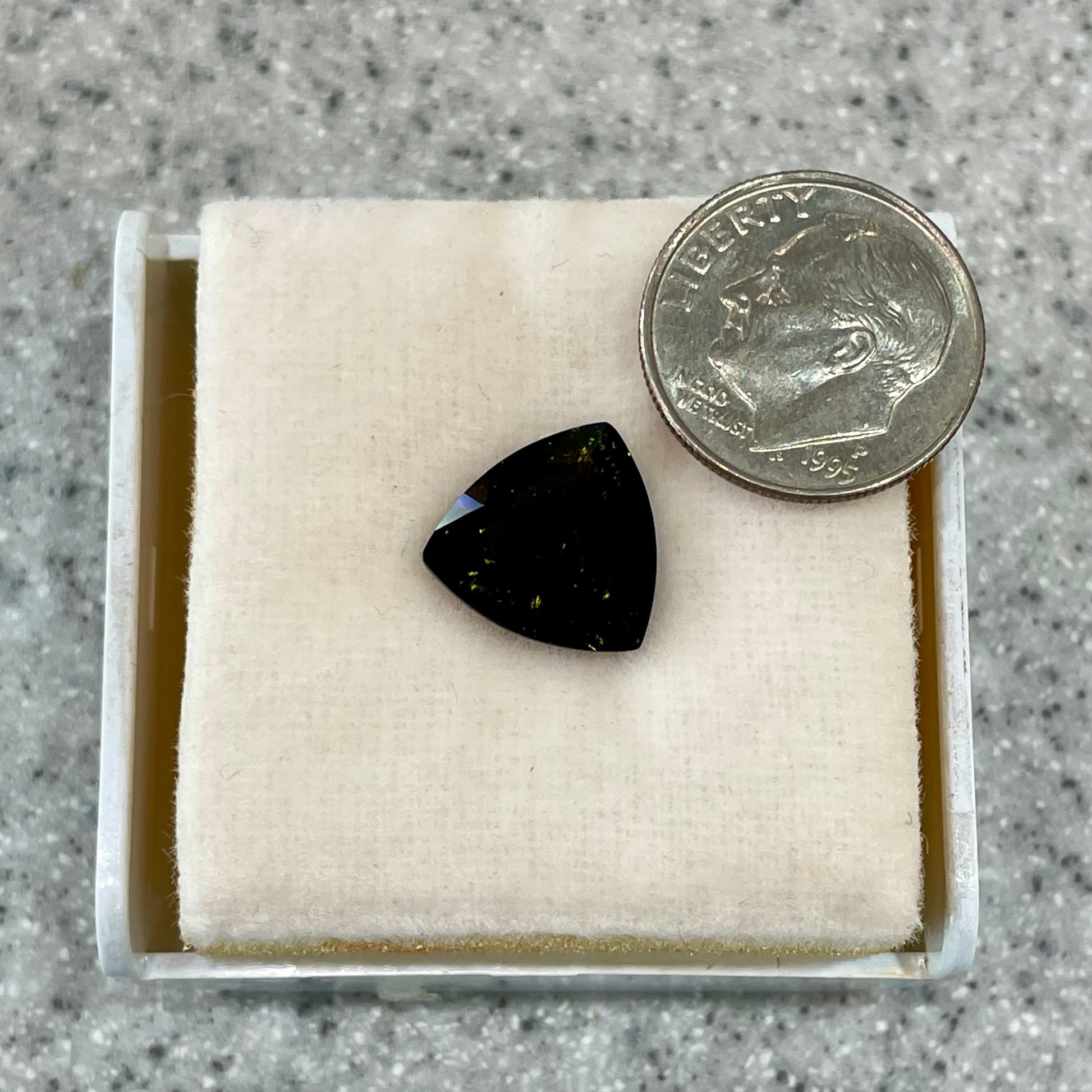 A faceted trillion cut moldavite gemstone that weighs 3.98 carats.  The stone is a dark green color.