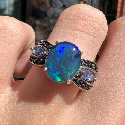 A sterling silver ring set with a black opal triplet, two marquise cut tanzanites, and round black spinel accent stones.