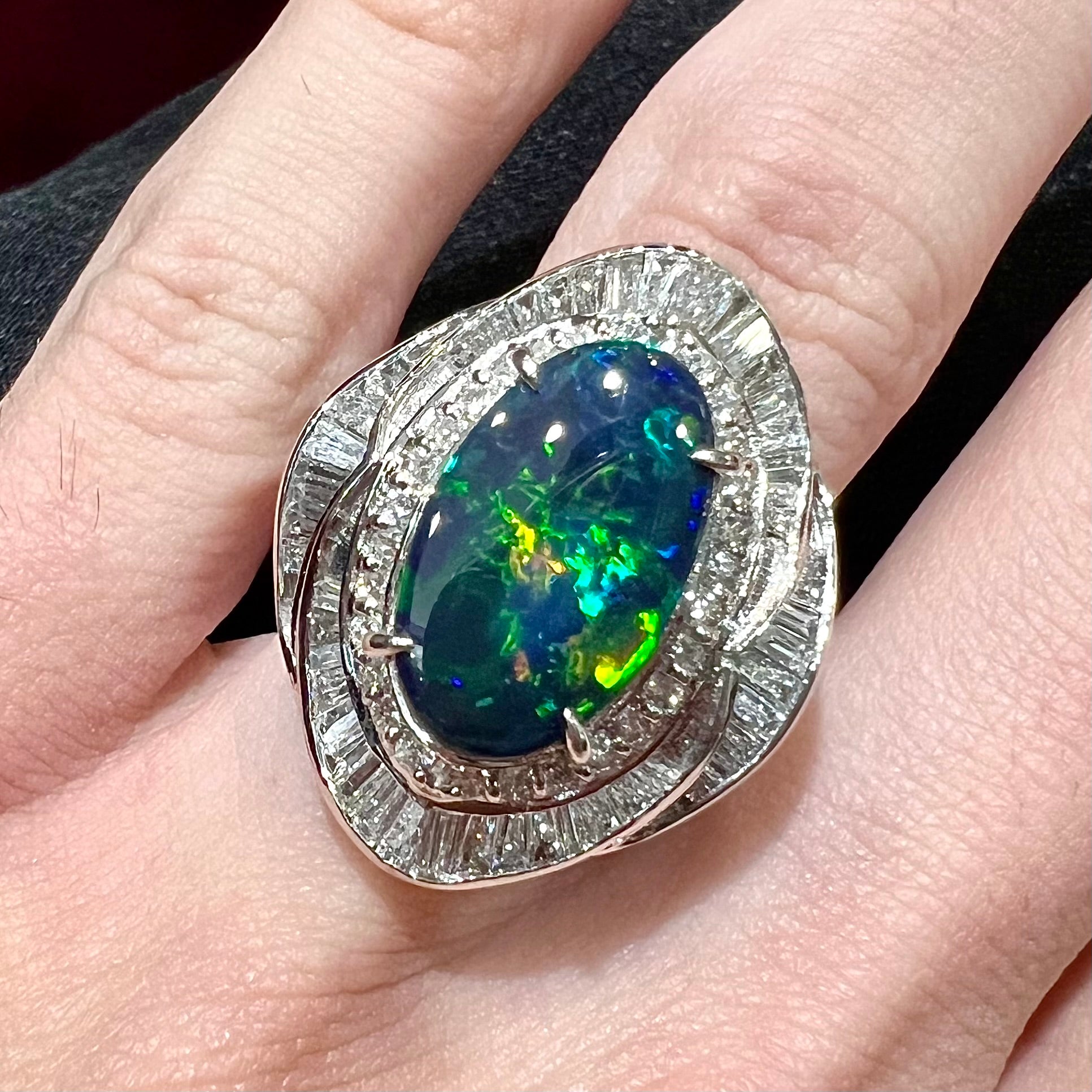 A ladies' platinum diamond halo ring set with a natural black opal stone from Lightning Ridge, Australia.