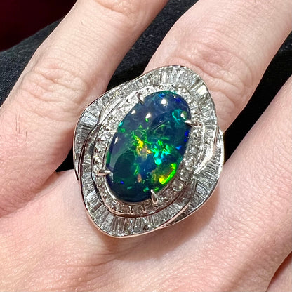 A ladies' platinum diamond halo ring set with a natural black opal stone from Lightning Ridge, Australia.