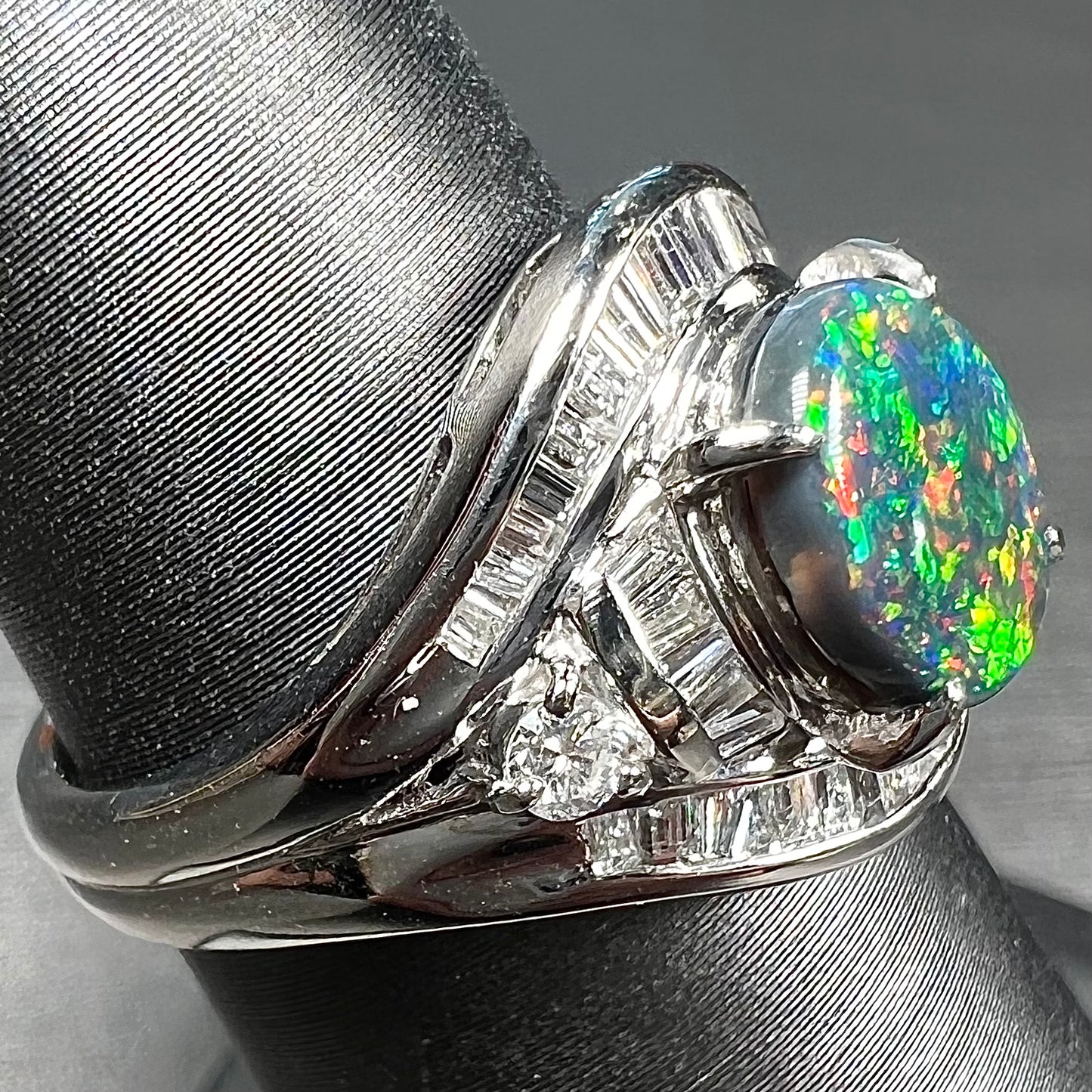 A platinum Lightning Ridge black opal ring set with baguette cut diamonds.  The opal is an oval cabochon cut.