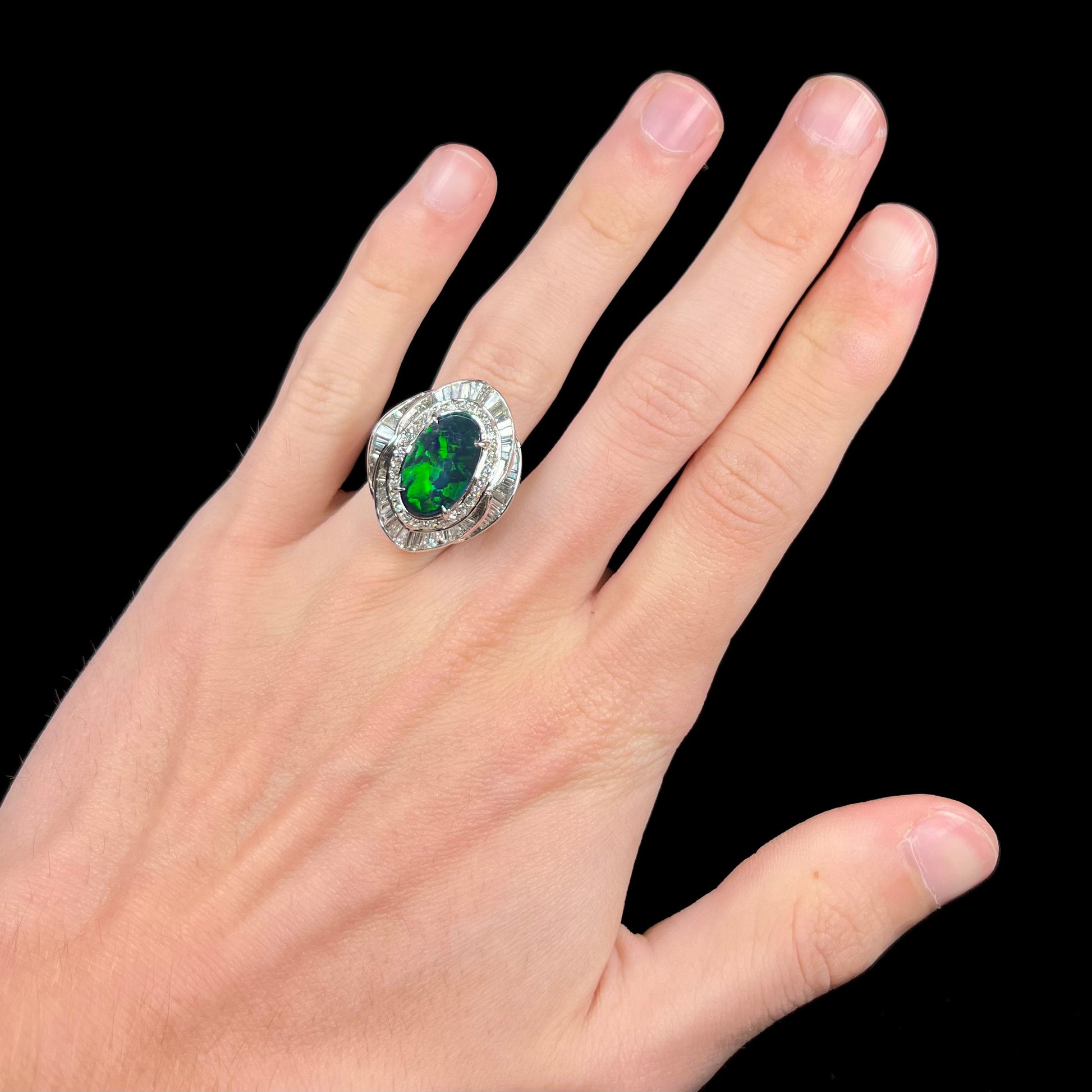 A ladies' platinum diamond halo ring set with a natural black opal stone from Lightning Ridge, Australia.
