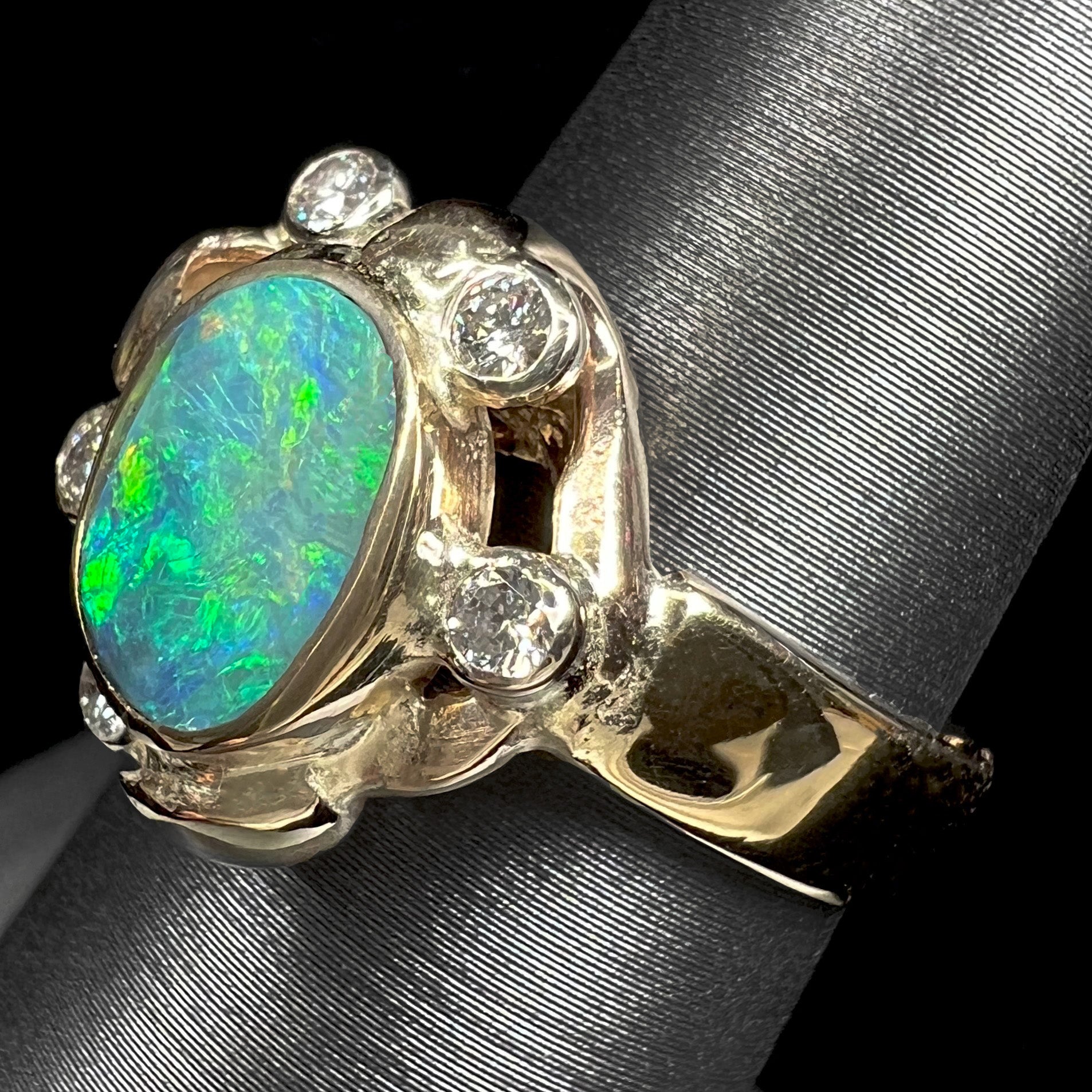 A ladies' yellow gold oval cut natural black opal ring set with five round accent diamonds.