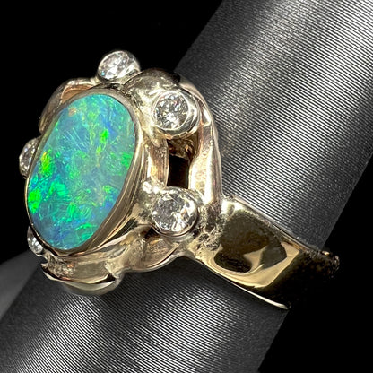 A ladies' yellow gold oval cut natural black opal ring set with five round accent diamonds.