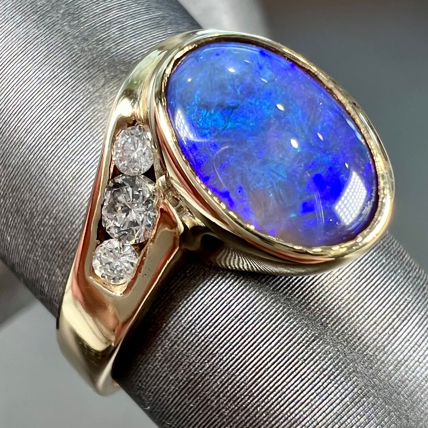 A yellow gold ring set with diamonds and a Lightning Ridge black opal from Australia.