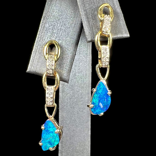 A pair of black opal doublet dangle earrings set in 10kt yellow gold with diamond accents.