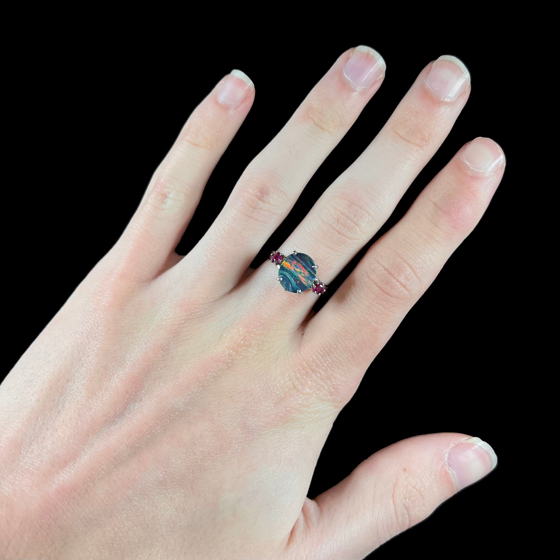 A ladies' 14kt white gold Australian black boulder opal doublet ring set with two round cut rubies.