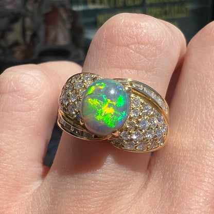 An 18kt yellow gold oval cabochon cut Lightning Ridge black opal ring.  The shank is set with round and baguette cut diamonds.