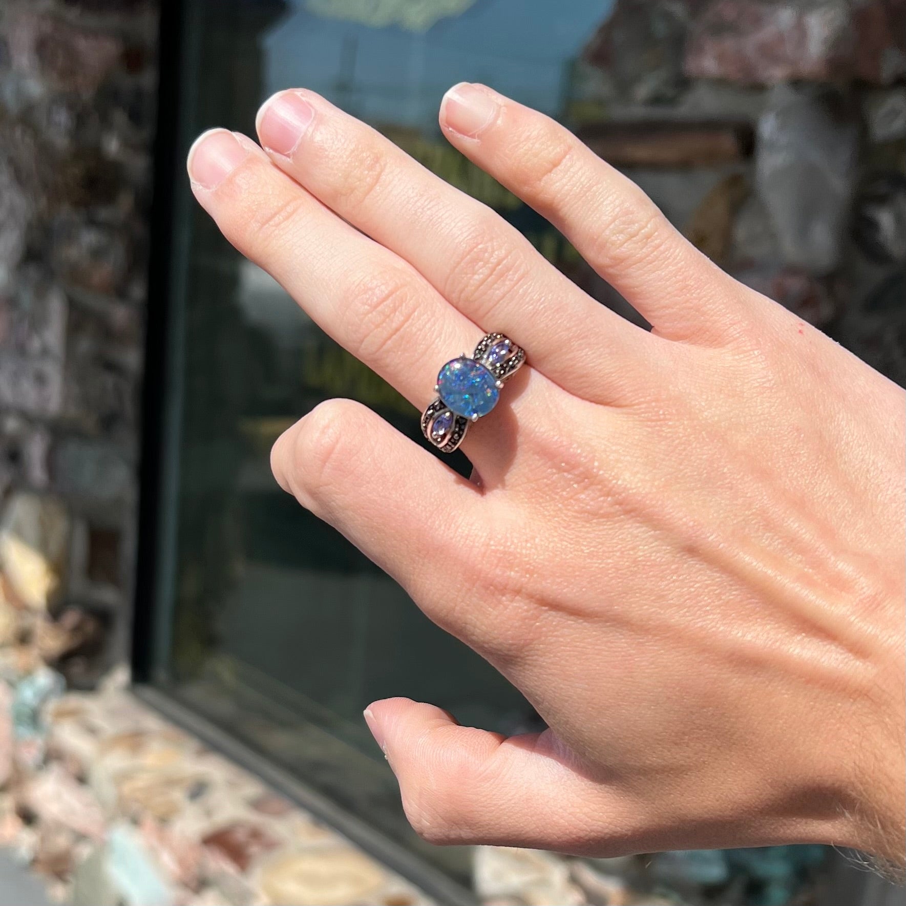A sterling silver black opal triplet ring set with black spinel and marquise cut tanzanite accent stones.