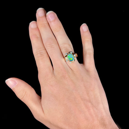 A ladies' yellow gold oval cut natural black opal ring set with five round accent diamonds.