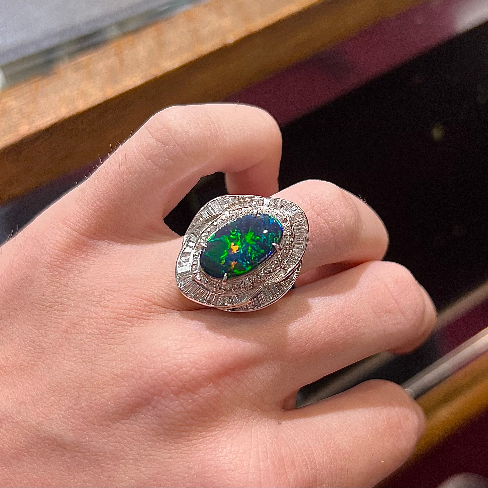 A ladies' platinum diamond halo ring set with a natural black opal stone from Lightning Ridge, Australia.