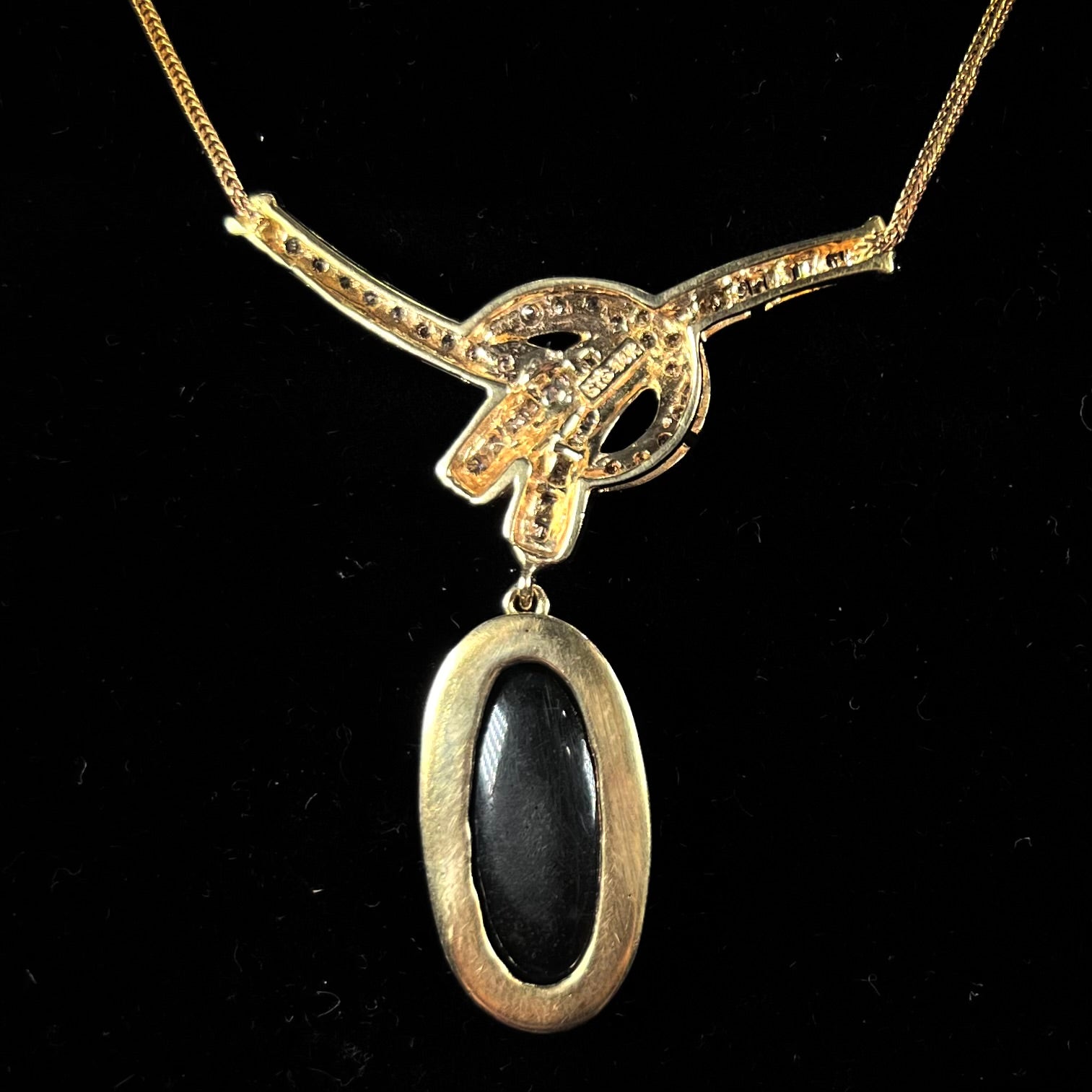 A gold black opal and diamond necklace.  There are round, princess cut, and baguette cut diamonds.