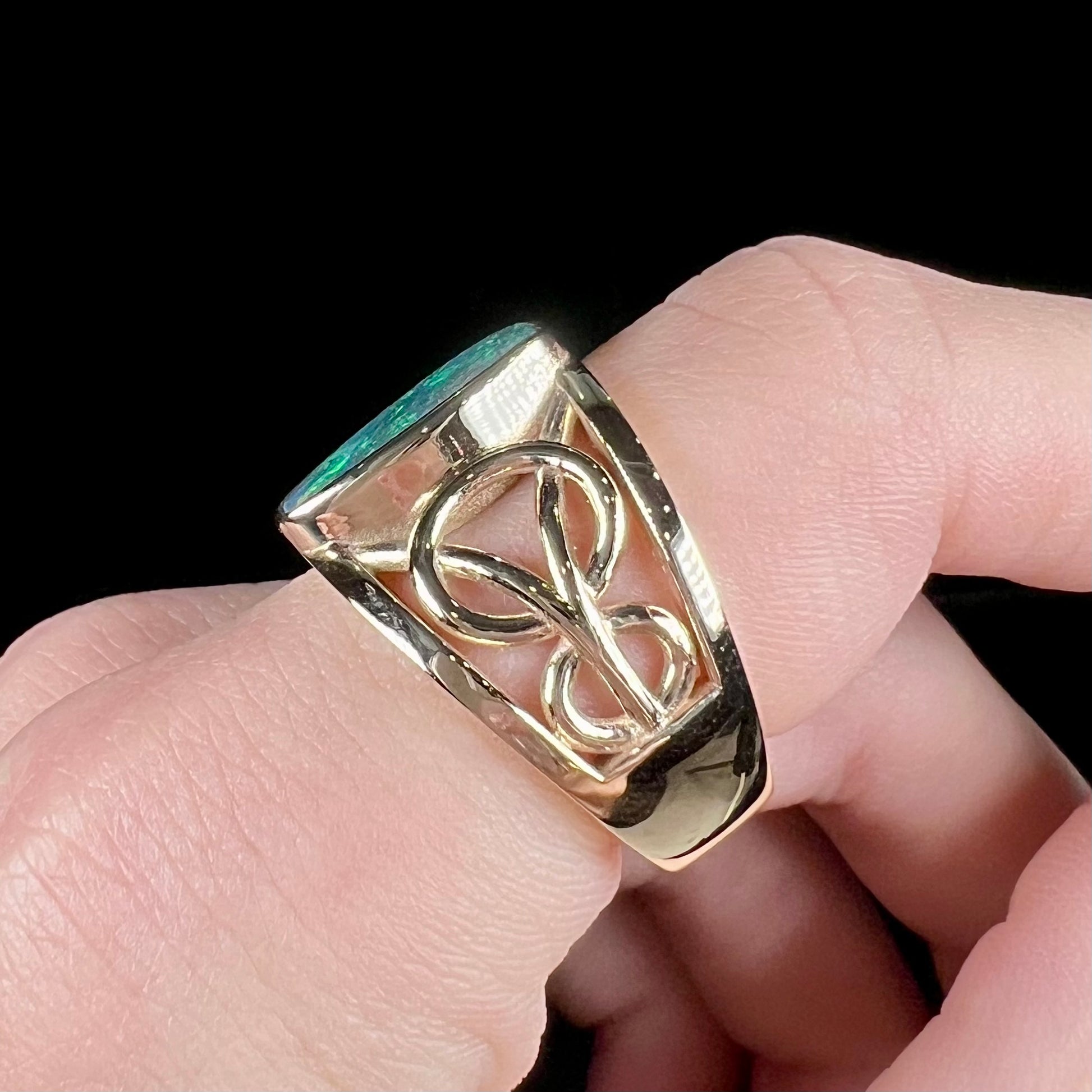 A men's natural Lightning Ridge, Australian black opal solitaire ring cast in yellow gold.