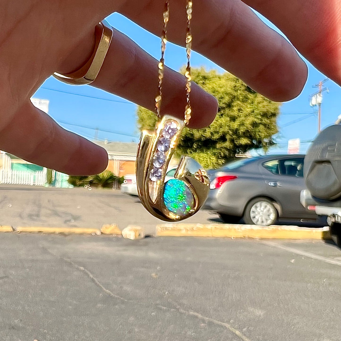 A Lightning Ridge black crystal opal necklace set with blue tanzanite in yellow gold.  Gold chain not included.